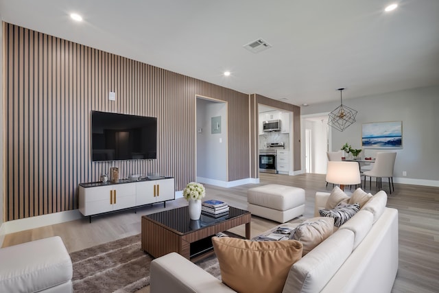 living room featuring recessed lighting, visible vents, baseboards, and wood finished floors