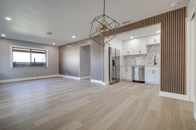 kitchen featuring stainless steel appliances, white cabinetry, visible vents, and light wood finished floors