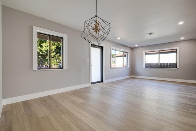 spare room featuring a wealth of natural light, visible vents, light wood-type flooring, and baseboards