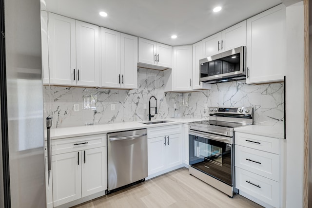 kitchen with a sink, stainless steel appliances, white cabinets, and light countertops