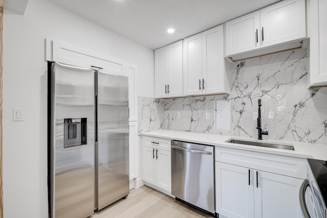 kitchen with a sink, decorative backsplash, white cabinets, and stainless steel appliances