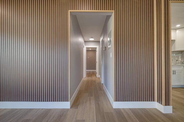 corridor featuring light wood finished floors and baseboards