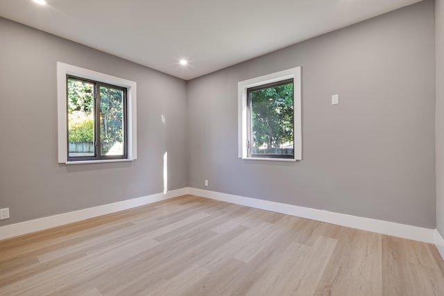 unfurnished room with a wealth of natural light, baseboards, and light wood-style floors