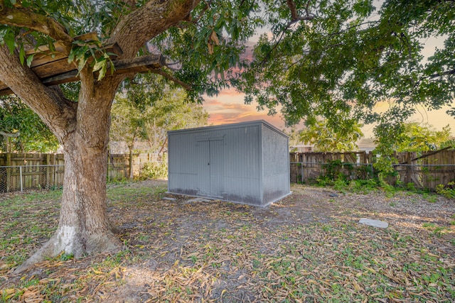 outdoor structure at dusk featuring an outbuilding, a shed, and a fenced backyard