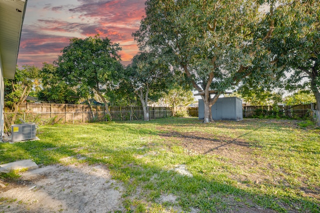 view of yard with a storage unit, a fenced backyard, an outdoor structure, and central AC