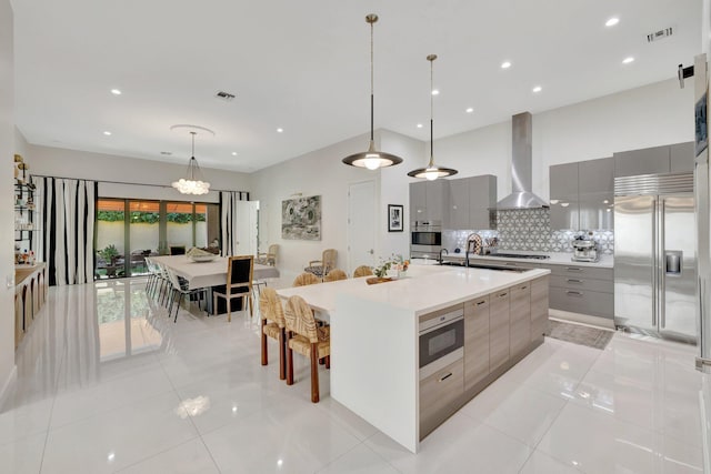 kitchen with gray cabinetry, modern cabinets, wall chimney exhaust hood, and stainless steel appliances