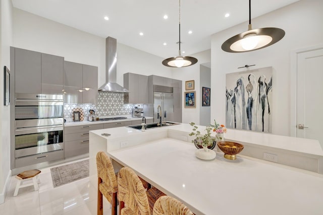 kitchen with modern cabinets, stainless steel appliances, gray cabinetry, and wall chimney exhaust hood