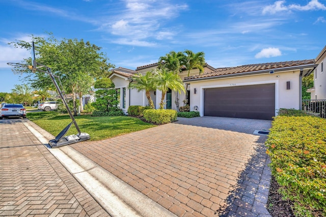 view of front of house with a front lawn, a tile roof, stucco siding, decorative driveway, and an attached garage