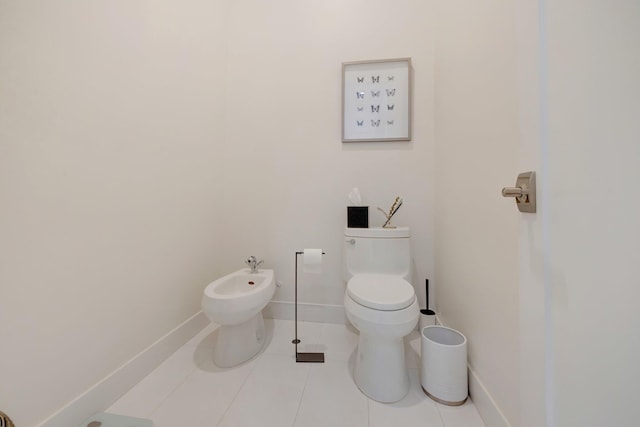 half bath with tile patterned flooring, toilet, a bidet, and baseboards