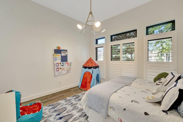 bedroom featuring an inviting chandelier, wood finished floors, and baseboards