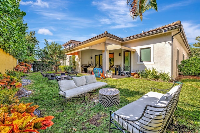 rear view of house featuring a tile roof, an outdoor living space, fence, a yard, and a patio area