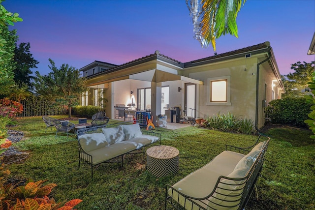 rear view of house with an outdoor living space, fence, a lawn, stucco siding, and a patio area