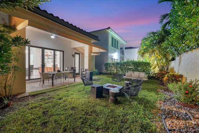 yard at dusk featuring fence, a fire pit, and a patio area