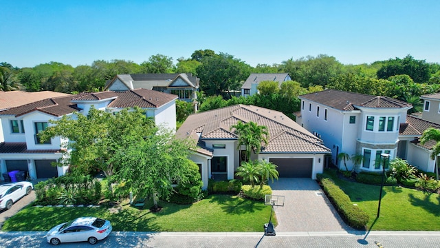 view of front of property featuring an attached garage, stucco siding, a front lawn, a tile roof, and decorative driveway