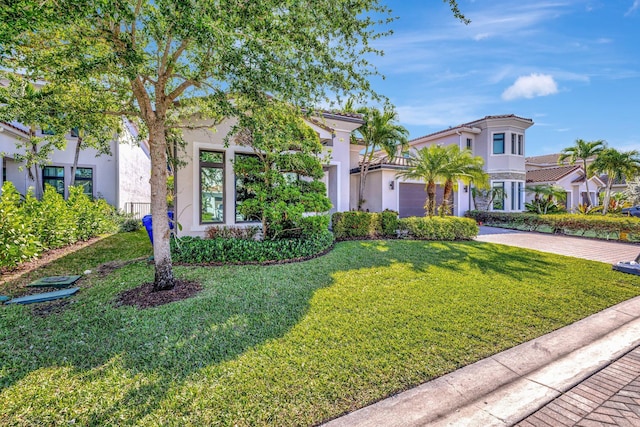 mediterranean / spanish house with a front yard, decorative driveway, a garage, and stucco siding