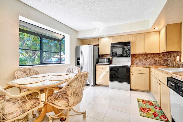 kitchen with tasteful backsplash, light brown cabinetry, light countertops, appliances with stainless steel finishes, and light tile patterned flooring