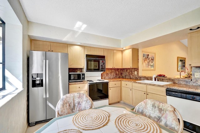 kitchen featuring light brown cabinets, appliances with stainless steel finishes, and a sink