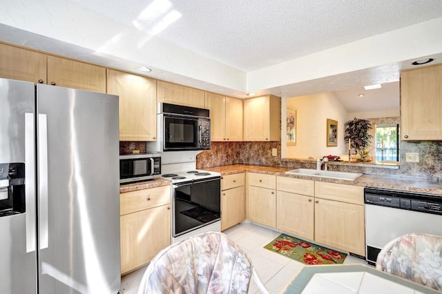 kitchen featuring decorative backsplash, light brown cabinets, appliances with stainless steel finishes, and a sink