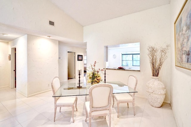 tiled dining space featuring visible vents, baseboards, and vaulted ceiling