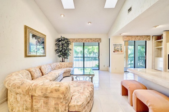 living area with lofted ceiling with skylight, a healthy amount of sunlight, and light tile patterned flooring