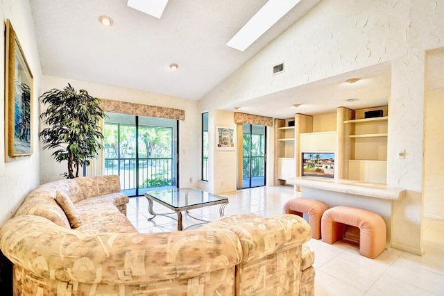 tiled living area featuring built in features, visible vents, high vaulted ceiling, and a skylight