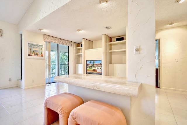 kitchen with built in features, light tile patterned flooring, and a textured ceiling