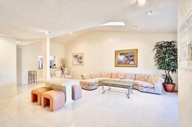 living area featuring tile patterned flooring, vaulted ceiling with skylight, and a textured ceiling