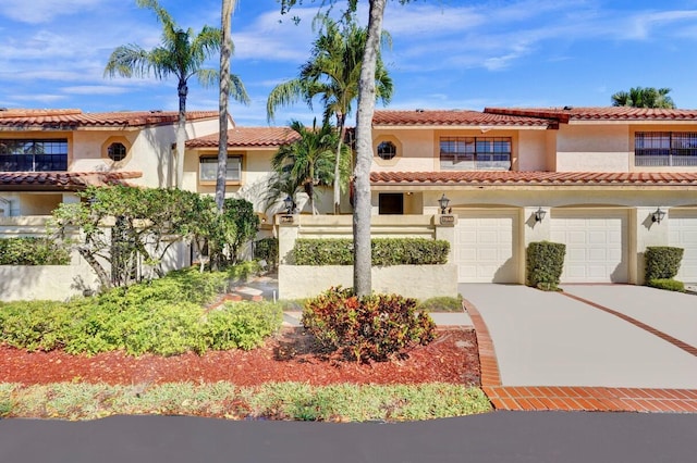 mediterranean / spanish-style house with a tiled roof, stucco siding, an attached garage, and concrete driveway