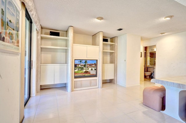 living room featuring light tile patterned floors, visible vents, and a textured ceiling