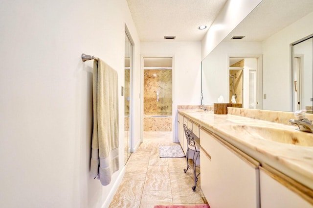 full bathroom with double vanity, visible vents, a shower with shower door, and a sink