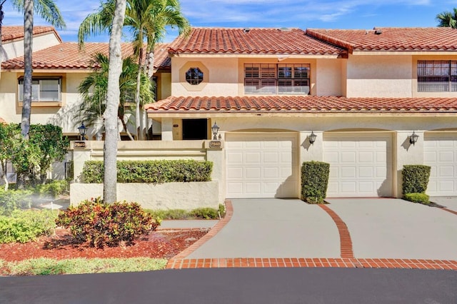 mediterranean / spanish home with concrete driveway, an attached garage, a tile roof, and stucco siding