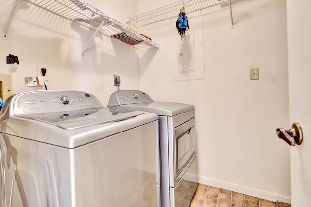 laundry area with electric panel, baseboards, separate washer and dryer, and laundry area