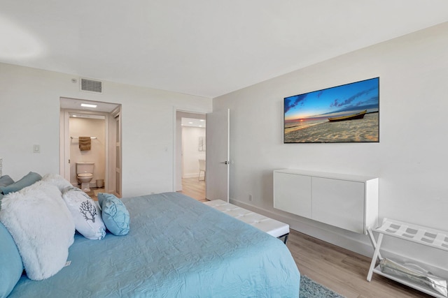 bedroom with visible vents, light wood-style flooring, and ensuite bath