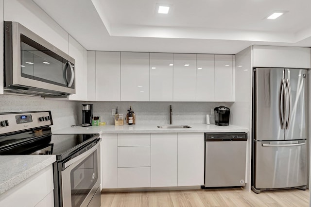 kitchen with white cabinetry, modern cabinets, appliances with stainless steel finishes, and a sink