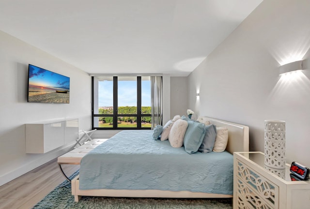 bedroom with floor to ceiling windows, wood finished floors, and baseboards