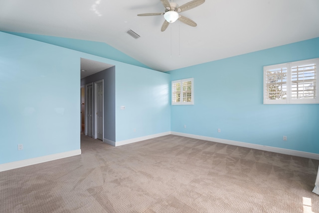 carpeted spare room featuring visible vents, baseboards, lofted ceiling, and ceiling fan