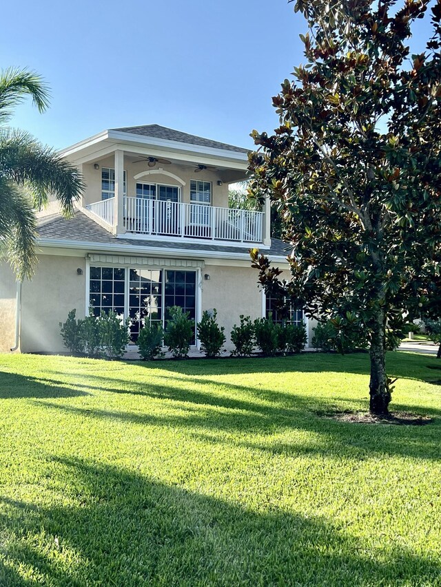 2010 NW Estuary Ct, Stuart, FL 34994 - view of front of home with a balcony, stucco siding, a front lawn, a ceiling fan, and a shingled roof