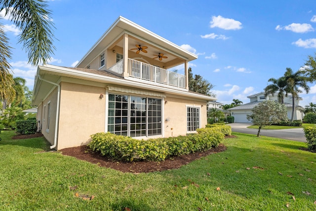 view of home's exterior with a yard, a balcony, a ceiling fan, and stucco siding