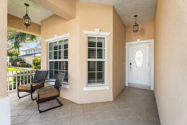 view of exterior entry with stucco siding and a porch