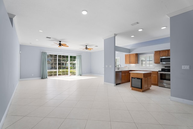 kitchen featuring a sink, stainless steel appliances, light countertops, crown molding, and open floor plan