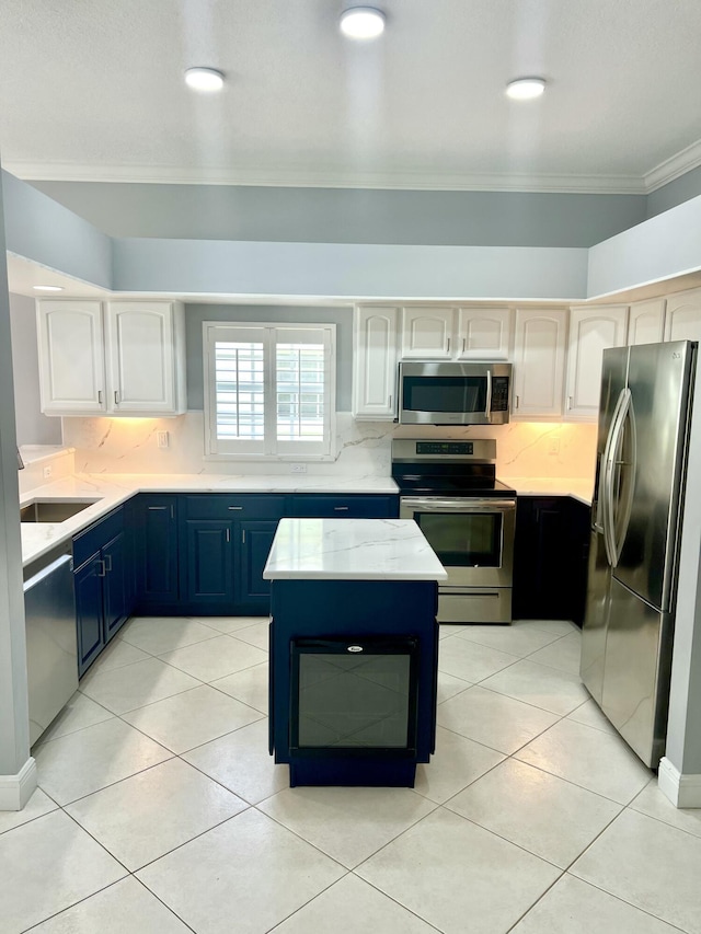 2010 NW Estuary Ct, Stuart, FL 34994 - kitchen featuring stainless steel appliances, ornamental molding, blue cabinetry, tasteful backsplash, and light tile patterned floors