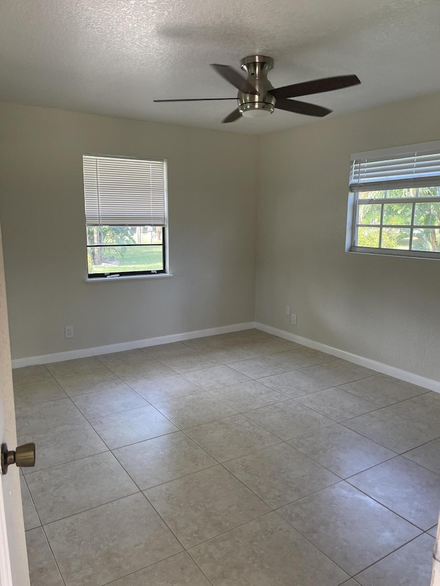 tiled empty room featuring a ceiling fan, baseboards, and a textured ceiling