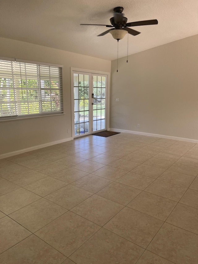 spare room with light tile patterned floors, a ceiling fan, baseboards, french doors, and a textured ceiling