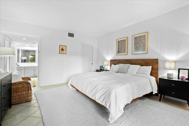 bedroom featuring light tile patterned floors, visible vents, and connected bathroom