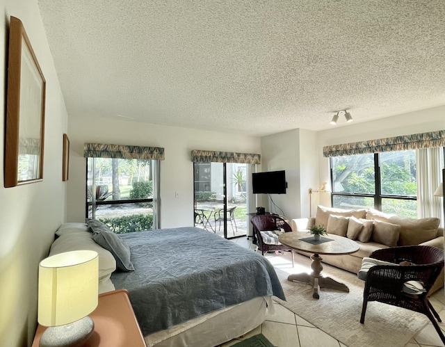 bedroom featuring tile patterned floors, track lighting, a textured ceiling, and access to outside