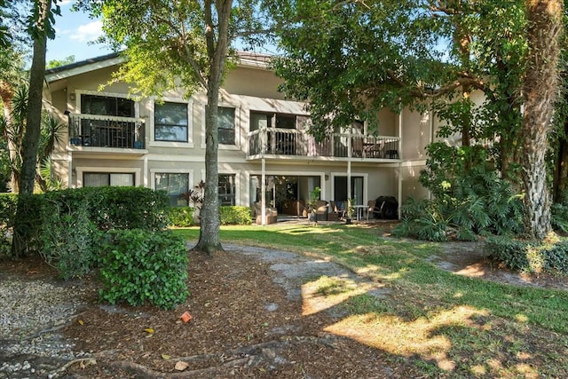 back of property featuring a balcony and stucco siding