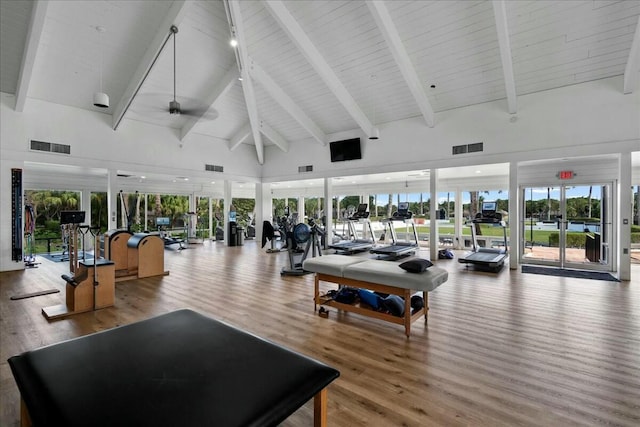 exercise room with visible vents, high vaulted ceiling, ceiling fan, and wood finished floors