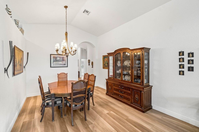 dining space featuring visible vents, lofted ceiling, arched walkways, light wood-style floors, and a chandelier