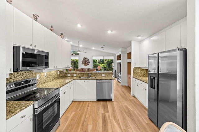 kitchen featuring a sink, appliances with stainless steel finishes, a peninsula, white cabinets, and vaulted ceiling