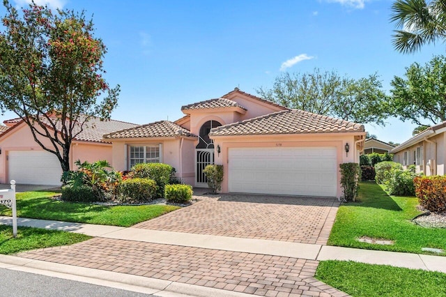 mediterranean / spanish-style home featuring a tiled roof, decorative driveway, a garage, and stucco siding